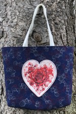 Quilted tote bag in navy blue with embroidery of roses framed in a heart shape.